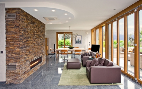 Architektenhaus von BAUFRITZ Luxushaus Tessin Wohnraum mit offenem Kamin im